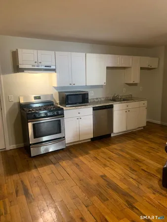 a kitchen with granite countertop a stove a sink and a microwave
