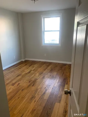 an empty room with wooden floor mirror and windows