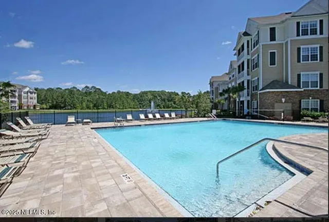 a view of swimming pool with outdoor seating and lake in the back