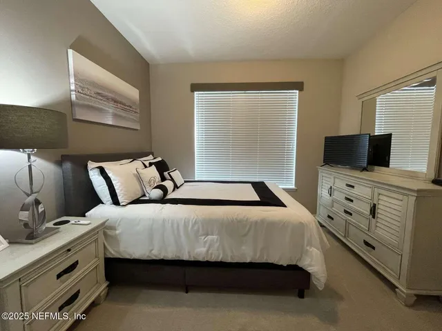 a bedroom with bed and flat tv screen on dresser