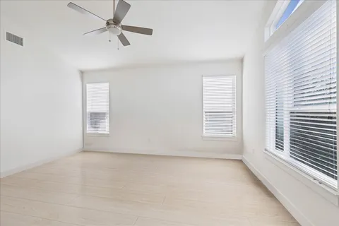 an empty room with a window and a fan