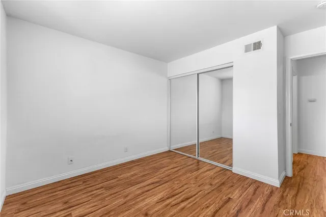 an empty room with wooden floor fireplace and windows