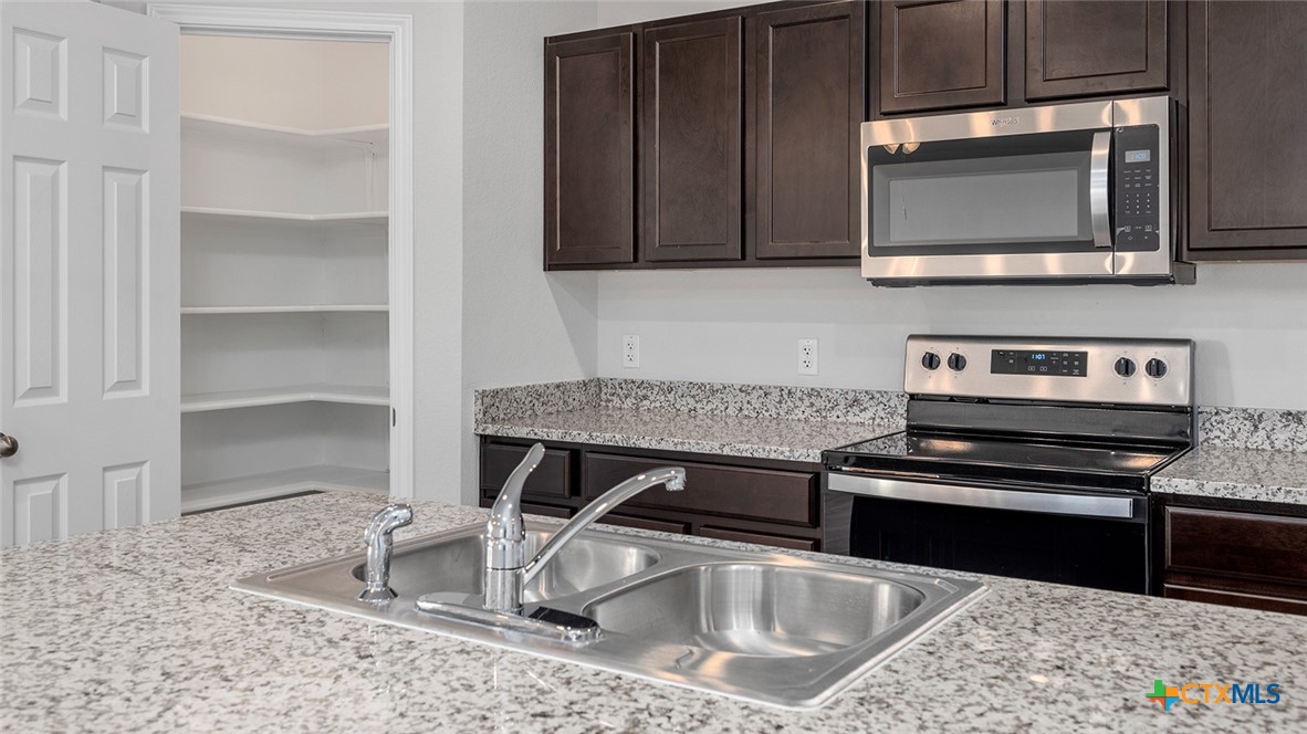 1503 Coriander Road Temple, TX 76501 - Photo 5 of 22 a kitchen with granite countertop a stove and a microwave