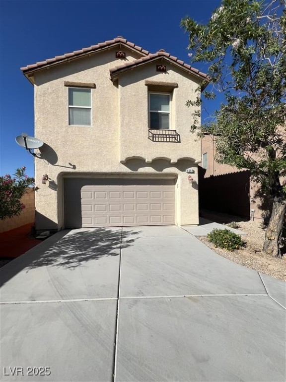 View of front facade featuring stucco siding, a garage, concrete driveway, and a tile roof