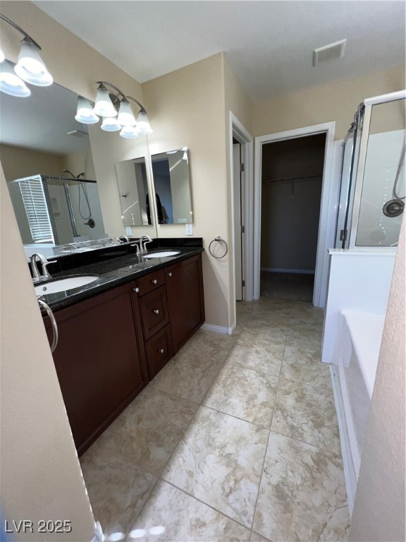 6592 Benvolio Court Las Vegas, NV 89141 - Photo 13 of 27 Bathroom with a walk in closet, a stall shower, double vanity, a garden tub, and light tile patterned flooring