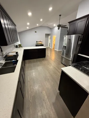 a kitchen with stainless steel appliances kitchen island granite countertop a refrigerator a stove and a microwave with wooden floor