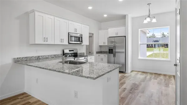 a kitchen with stainless steel appliances granite countertop a sink refrigerator and cabinets