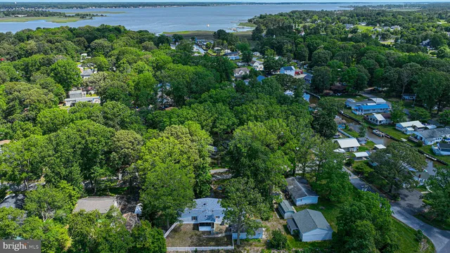 an aerial view of a residential houses with outdoor space and trees all around