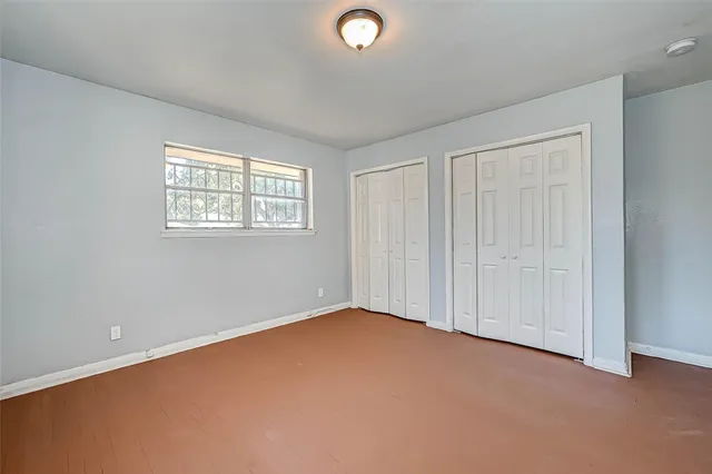 an empty room with windows & cabinet