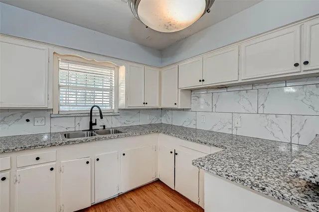 a kitchen with granite countertop white cabinets and a sink