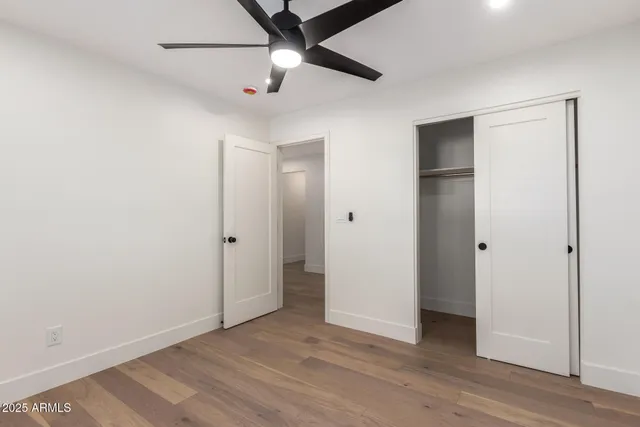 an empty room with wooden floor and ceiling fan