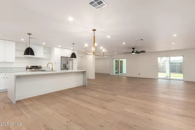 a large kitchen with kitchen island white cabinets and stainless steel appliances
