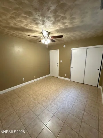 an empty room with wooden floor ceiling fan and windows