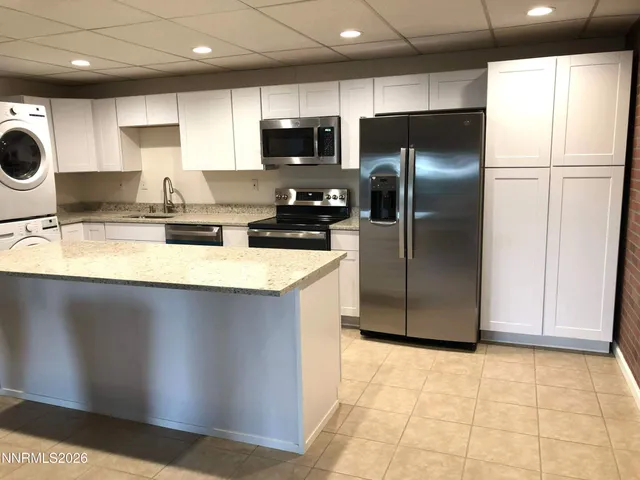 a kitchen with stainless steel appliances granite countertop a refrigerator a sink and a stove