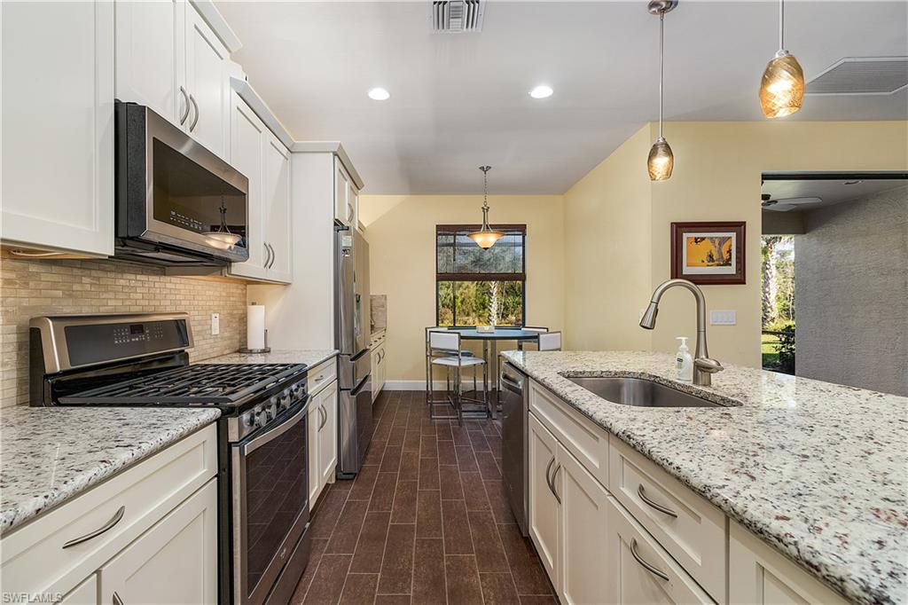 16309 Winfield Lane Naples, FL 34110 - Photo 11 of 35 a kitchen with stainless steel appliances granite countertop a sink a stove oven and a kitchen island