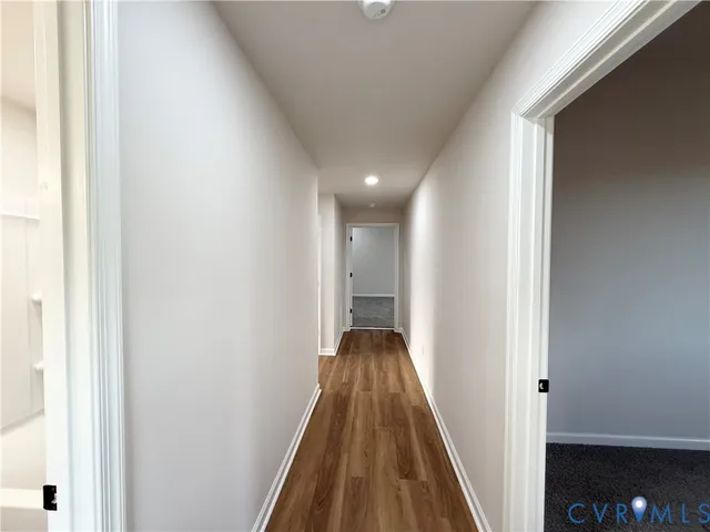 a view of a hallway with wooden floor and a bathroom