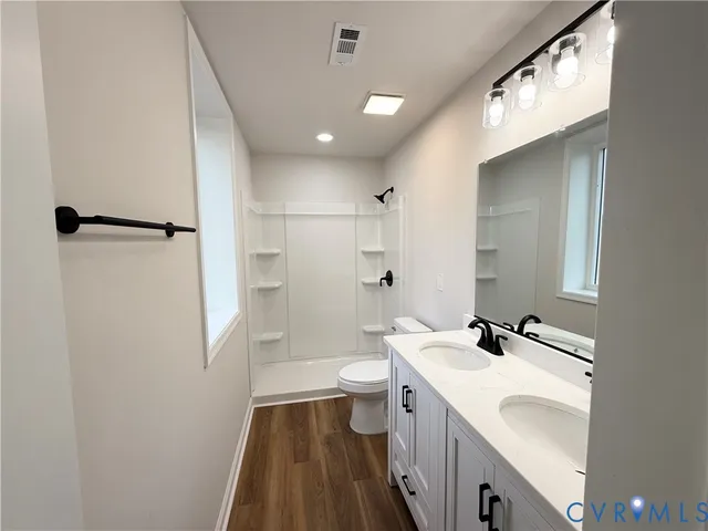 a bathroom with a sink a toilet a shower and a mirror