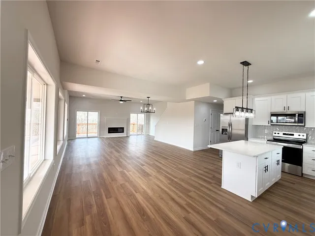 a large kitchen with a large window a stainless steel appliances and wooden floor