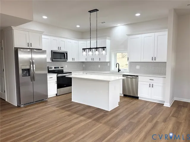 a kitchen with white cabinets stainless steel appliances and a window