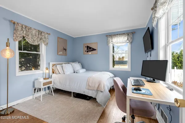 a bedroom with a bed computer on desk and a window