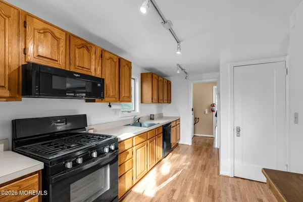 a kitchen with stainless steel appliances a stove a sink cabinets and a wooden floor