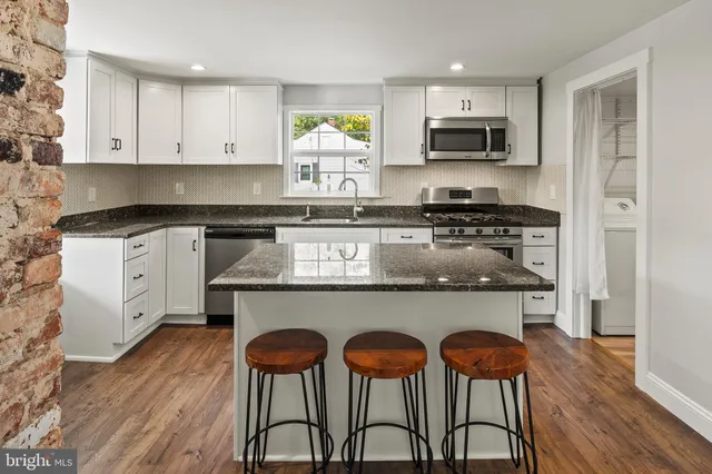 a kitchen with stainless steel appliances granite countertop a stove a sink a microwave a refrigerator and cabinets