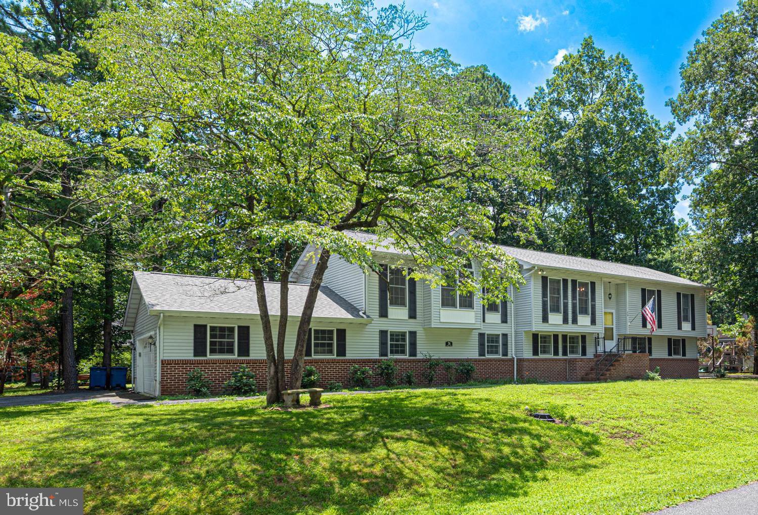 a view of house with a big yard and large trees