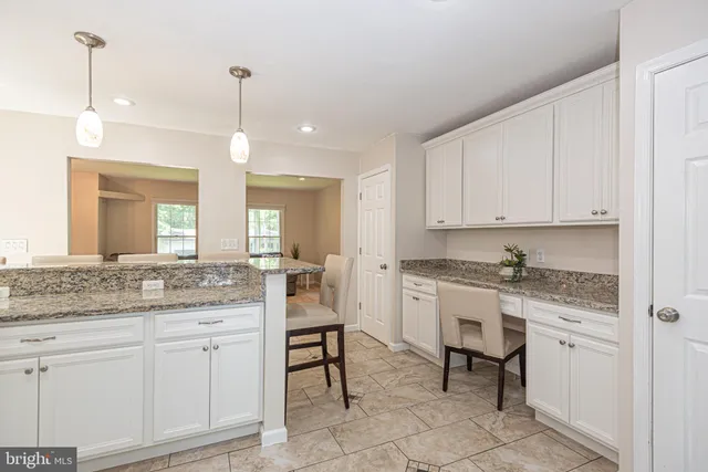 a bathroom with a granite countertop toilet a sink a mirror a window and vanity