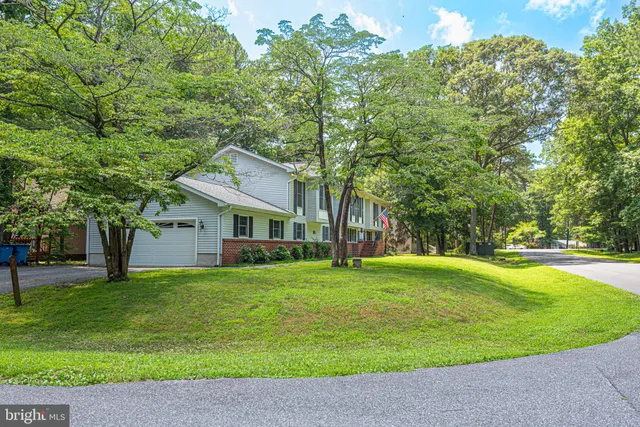 a view of a house with a big yard and large trees