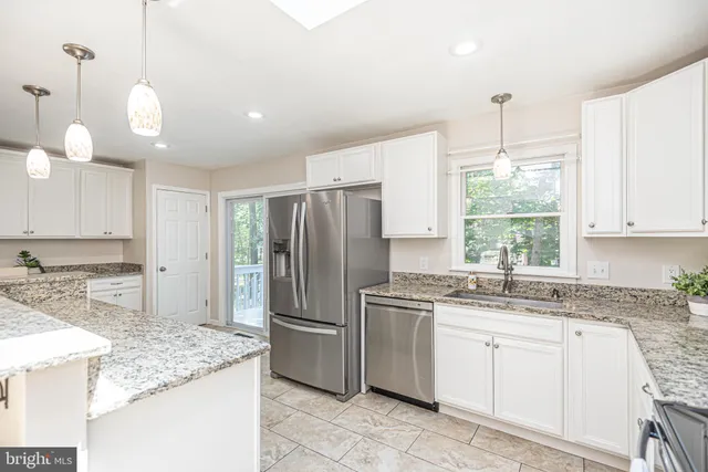 a open white kitchen with center island and stainless steel appliances