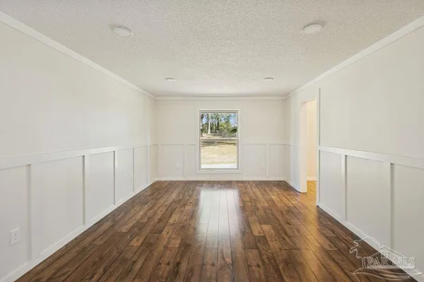 a view of empty room with wooden floor and furniture