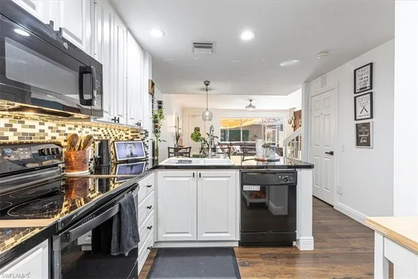a kitchen with kitchen island granite countertop a sink cabinets and stainless steel appliances