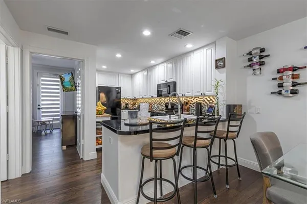 a kitchen with stainless steel appliances kitchen island granite countertop a dining table chairs and white cabinets