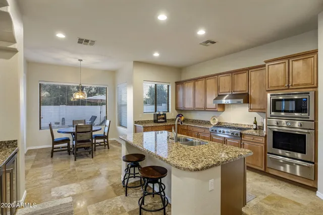 a kitchen with granite countertop kitchen island stainless steel appliances a stove a table and chairs