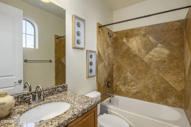 a bathroom with a granite countertop bathtub shower sink vanity and toilet