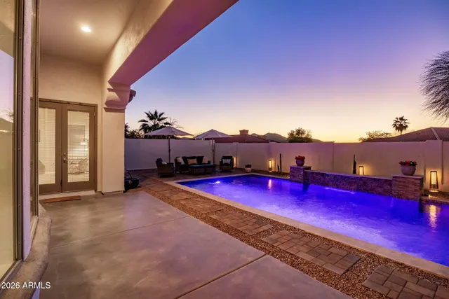 a view of a pool with lawn chairs and wooden fence