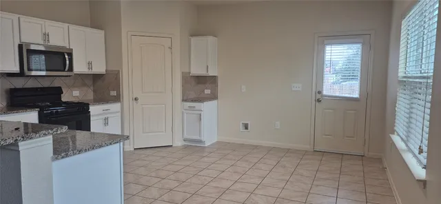 a kitchen with granite countertop a refrigerator and a stove top oven