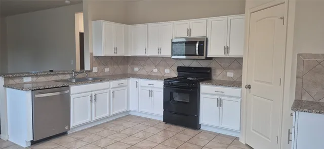 a kitchen with white cabinets and stainless steel appliances