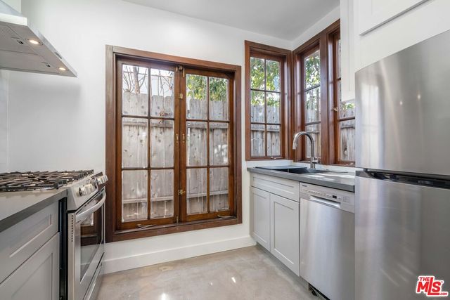 a view of a kitchen with stainless steel appliances granite countertop a stove a sink and a refrigerator