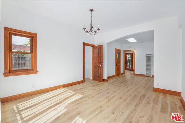 a view of an empty room with window and wooden floor