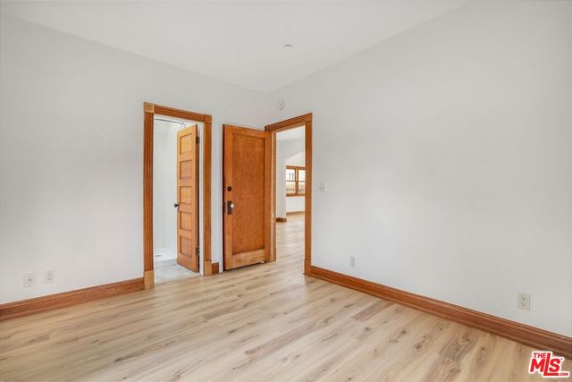 a view of an empty room with wooden floor and closet
