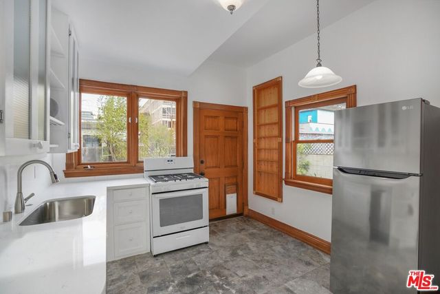 a kitchen with stainless steel appliances granite countertop a refrigerator a sink a stove and a window