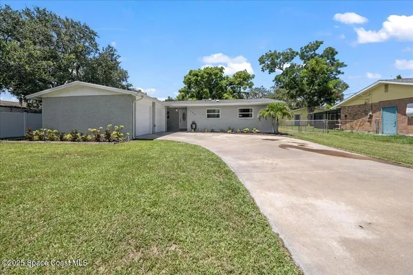 a front view of house with yard and trees in the background