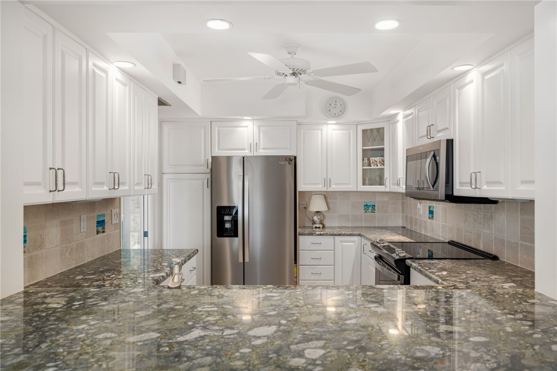 1875 Bay Road, Unit 215H Vero Beach, FL 32963 - Photo 11 of 36 a kitchen with stainless steel appliances granite countertop a refrigerator and a stove top oven