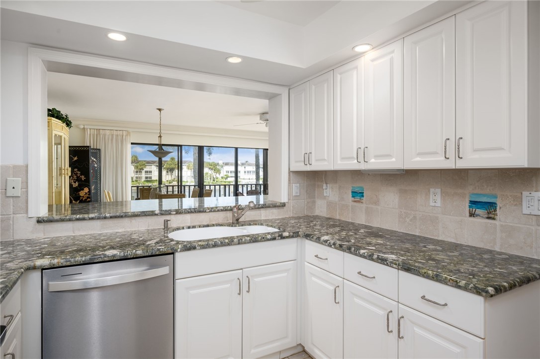 1875 Bay Road, Unit 215H Vero Beach, FL 32963 - Photo 13 of 36 a kitchen with granite countertop white cabinets and a sink