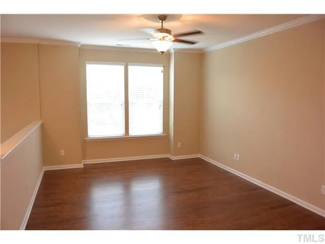 an empty room with wooden floor chandelier fan and windows