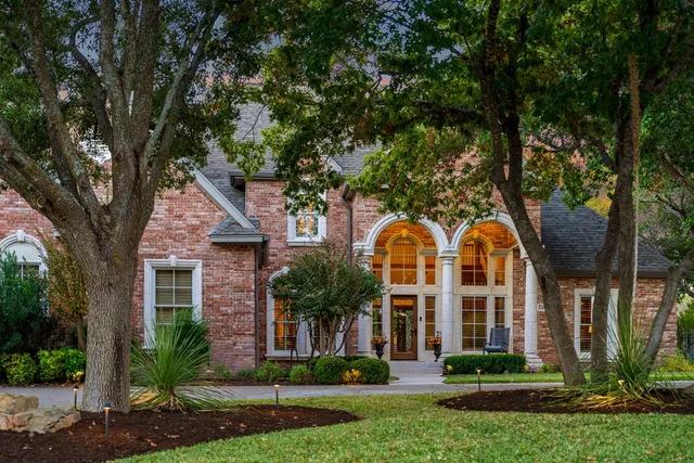 front view of house with a yard and large trees