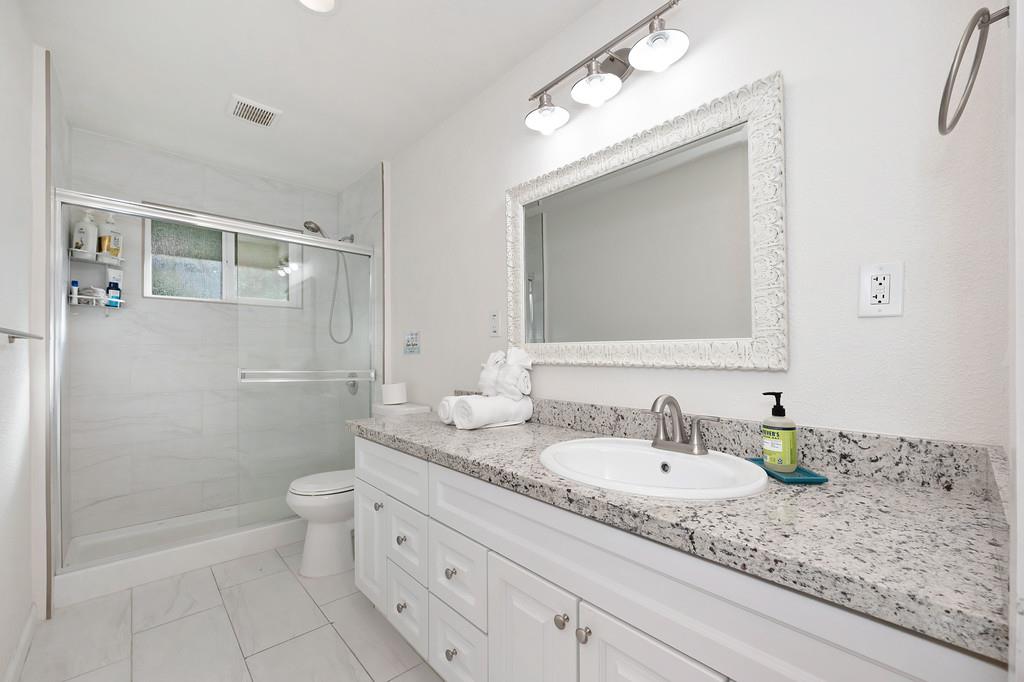 3191 Fort Jim Road Placerville, CA 95667 - Photo 26 of 30 a bathroom with a granite countertop sink a toilet and a mirror
