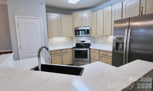 a kitchen with stainless steel appliances kitchen island granite countertop a refrigerator a stove a sink a washer and dryer with wooden floor