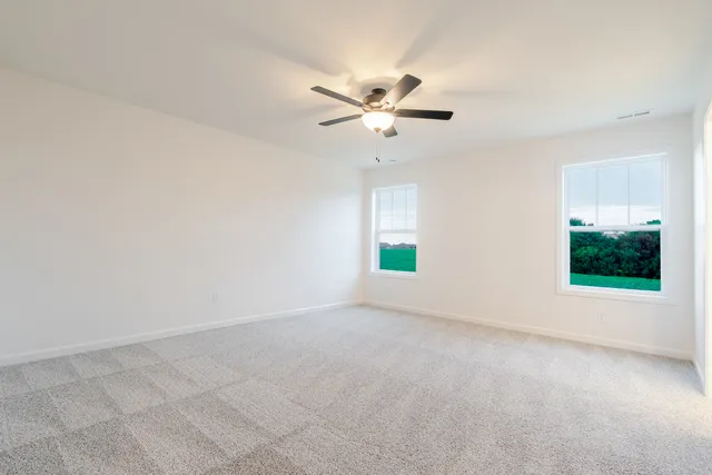 an empty room with windows and fan chandelier fan